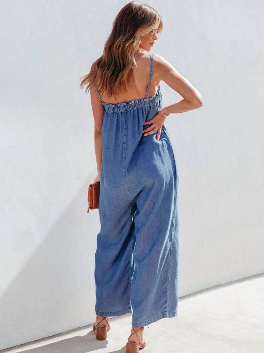 Woman wearing a blue denim jumpsuit against a white background