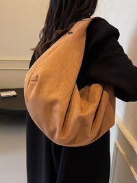 Person wearing a brown leather shoulder bag indoors.