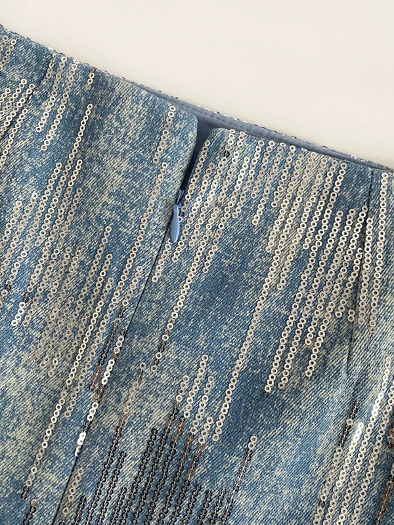 Close-up of blue denim fabric with chain details on a white background