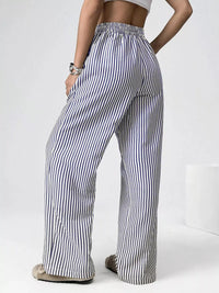 Person wearing black and white striped pants on a plain background