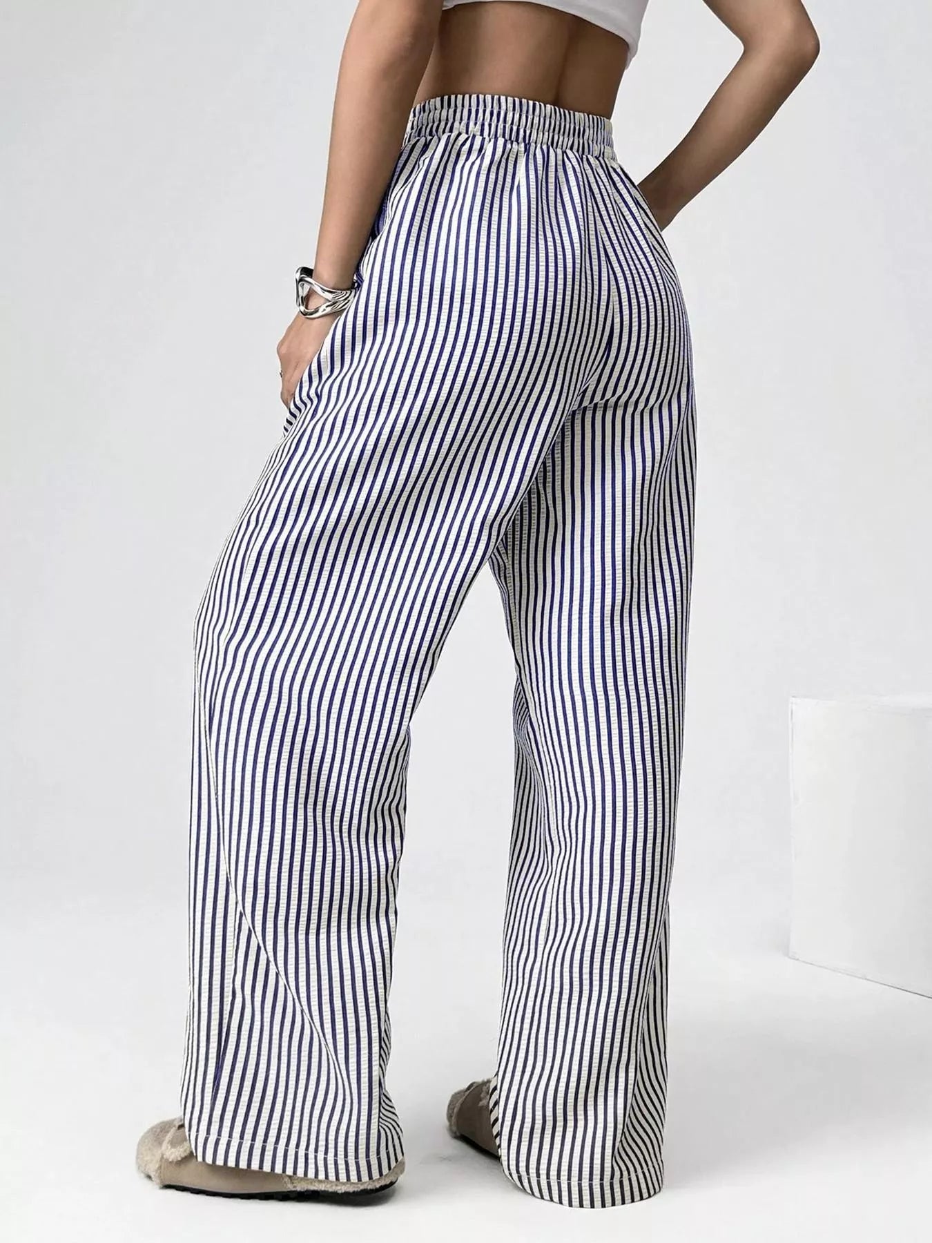Person wearing black and white striped pants on a plain background