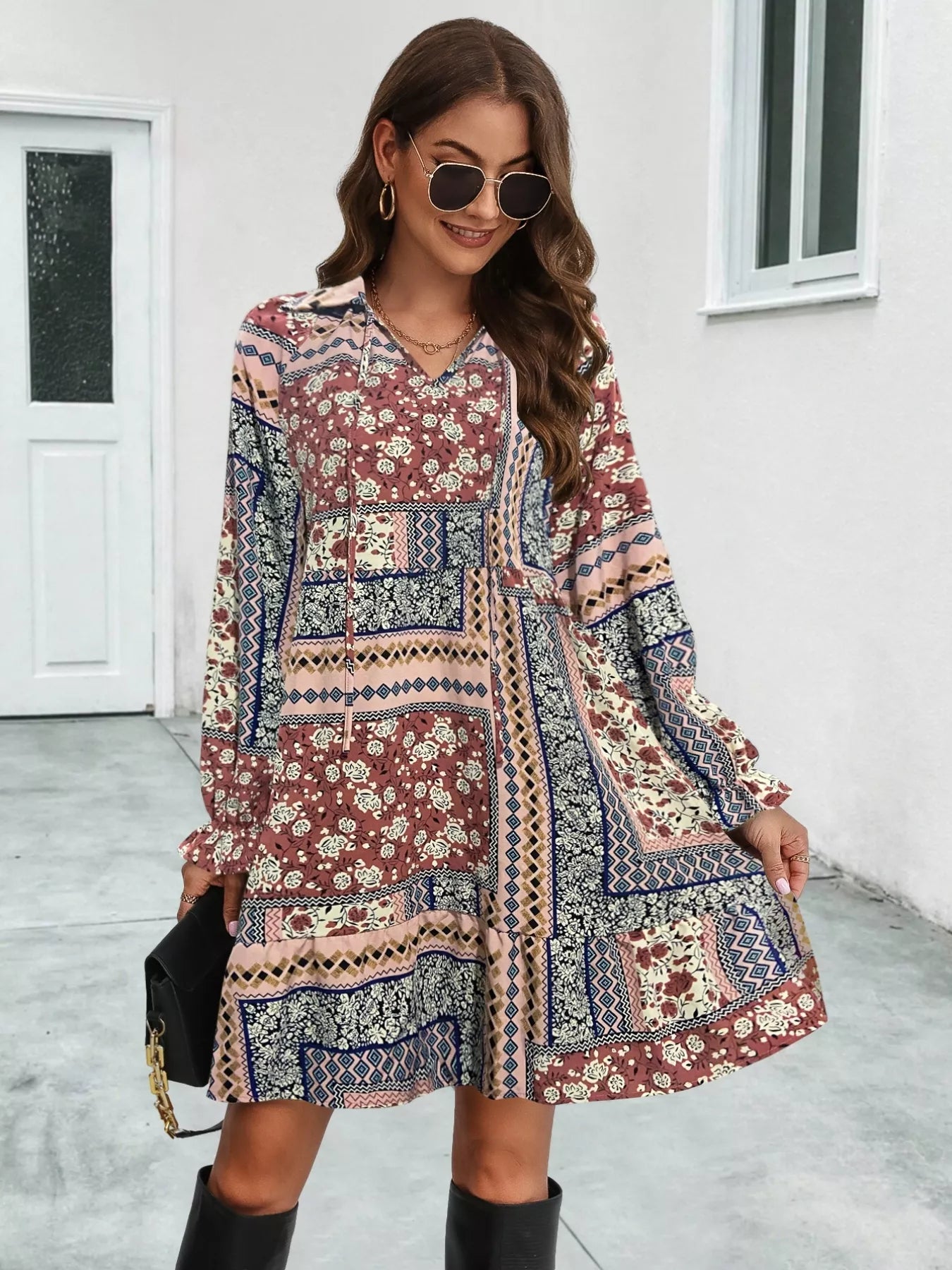 Woman wearing a patterned dress with long sleeves in an outdoor setting.