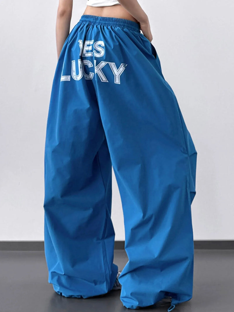 Blue wide-leg pants with 'YES LUCKY' text on a plain background