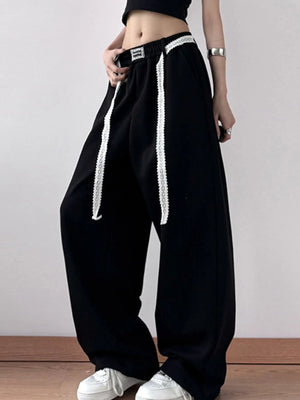 Black pants with white stripes worn by a person on a plain background