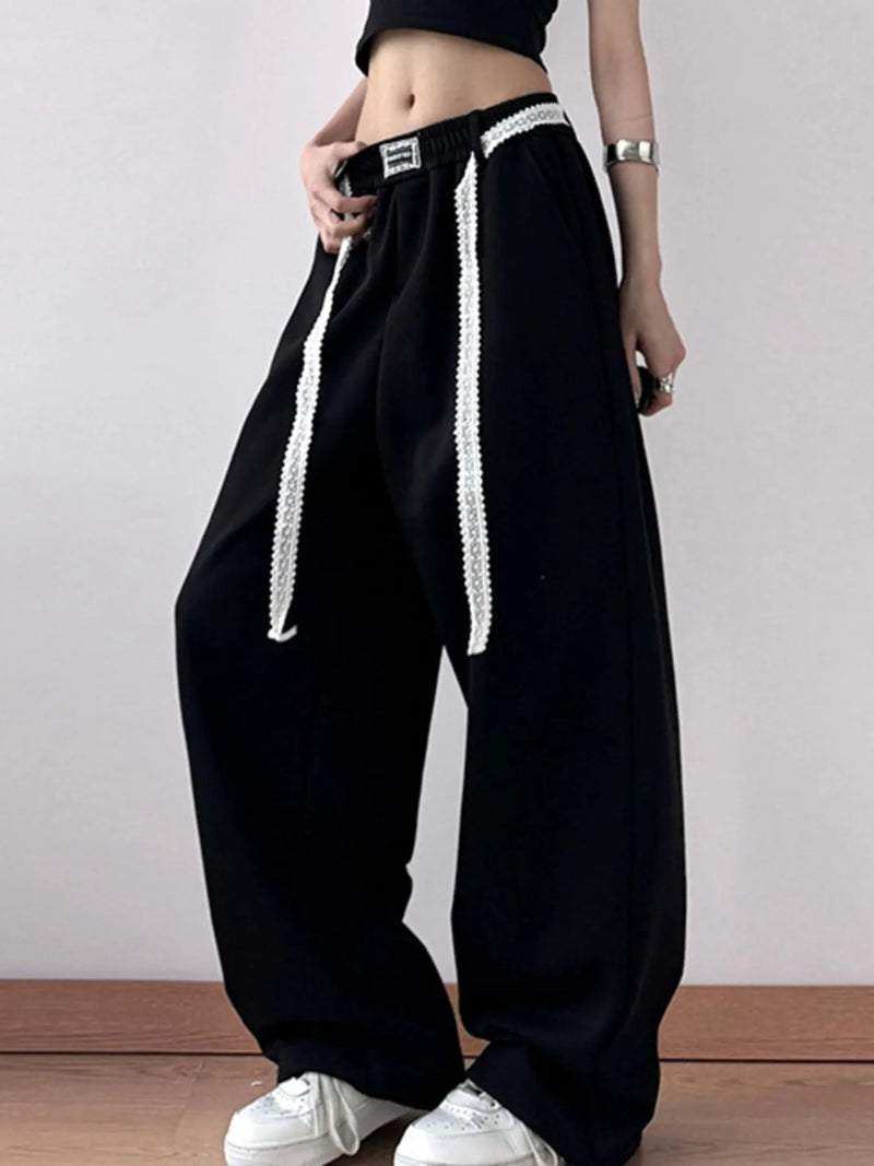 Black pants with white stripes worn by a person on a plain background