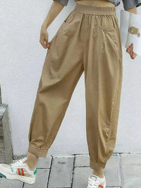 Person wearing beige jogger pants and white sneakers against a light gray wall.