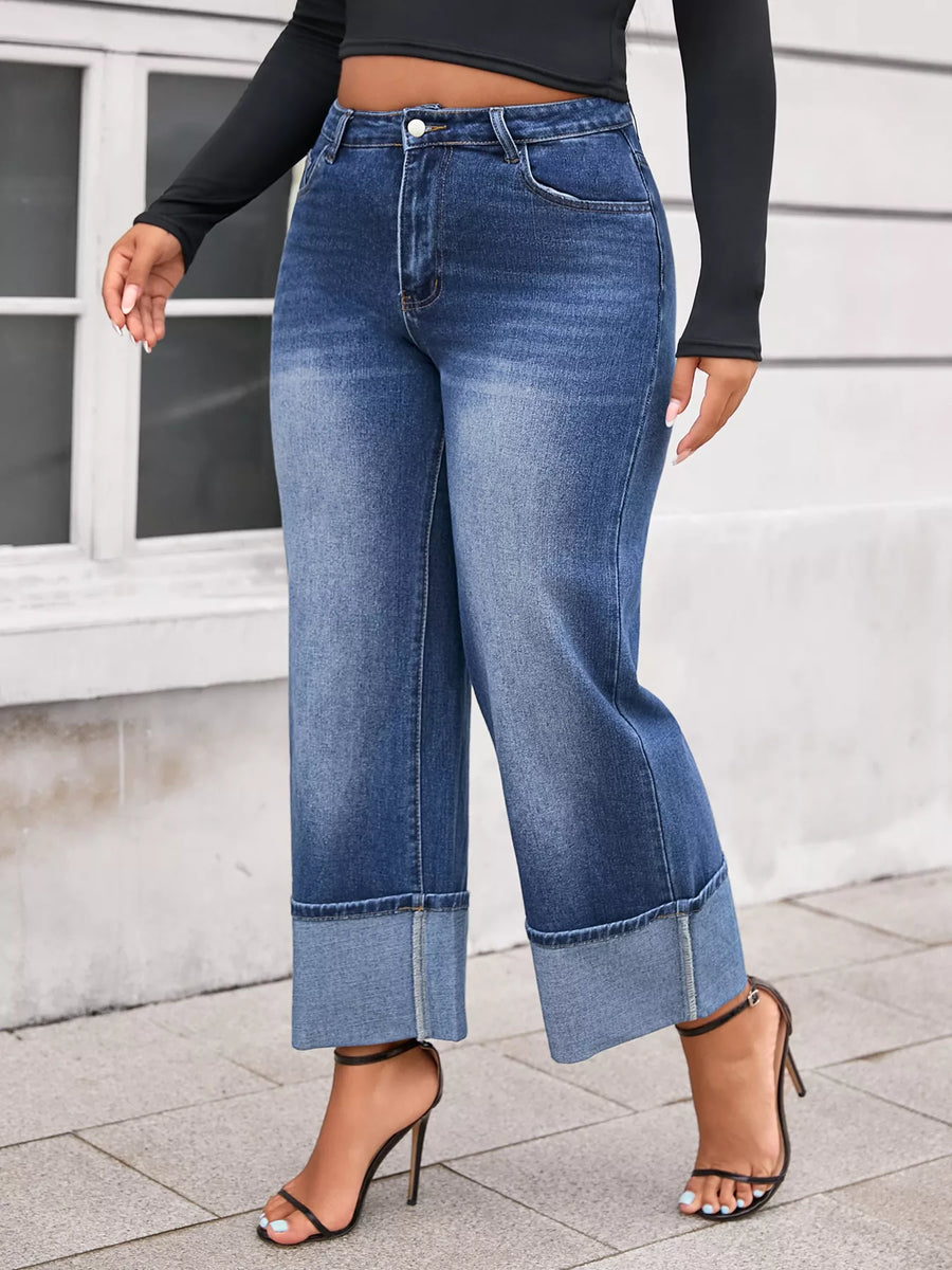 Person wearing blue jeans and black high-heeled shoes on a light-colored pavement.