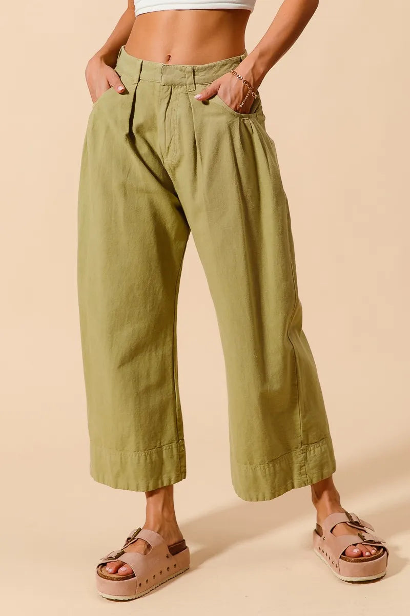 Person wearing green wide-leg pants on a beige background