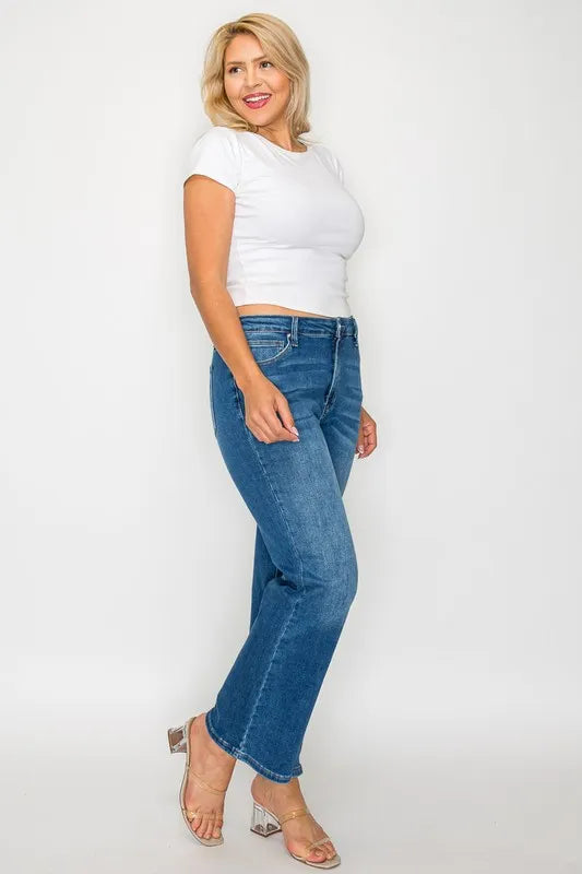 Woman wearing a white crop top and blue jeans on a white background