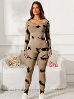 Woman wearing a beige bodysuit with black abstract patterns in a white room.