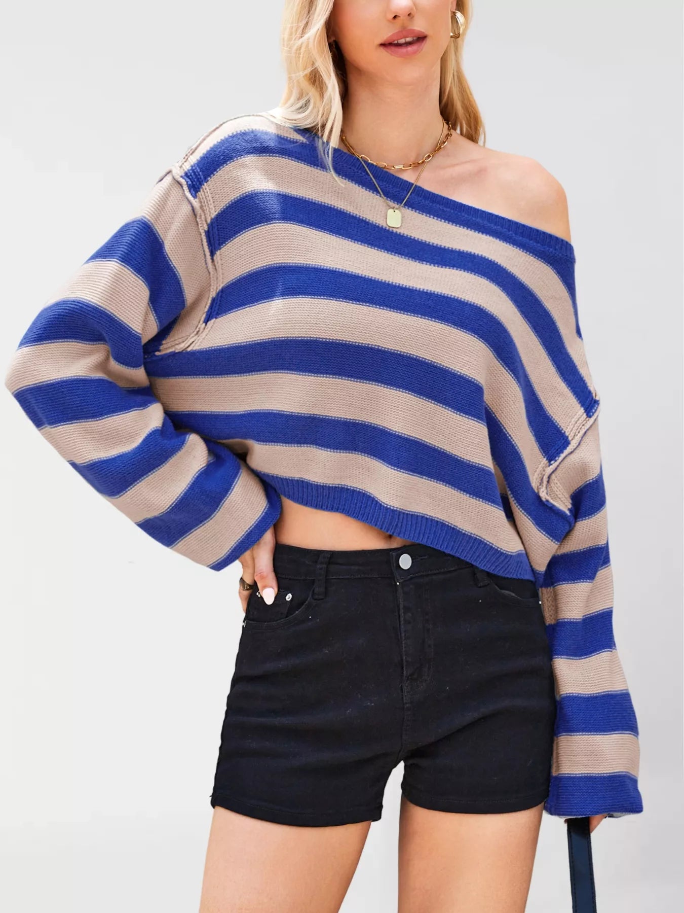 Woman wearing a blue and beige striped sweater with black shorts on a white background