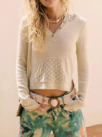Person wearing a light-colored cardigan with lace details and colorful pants.