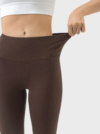 Brown leggings being stretched by a person on a white background