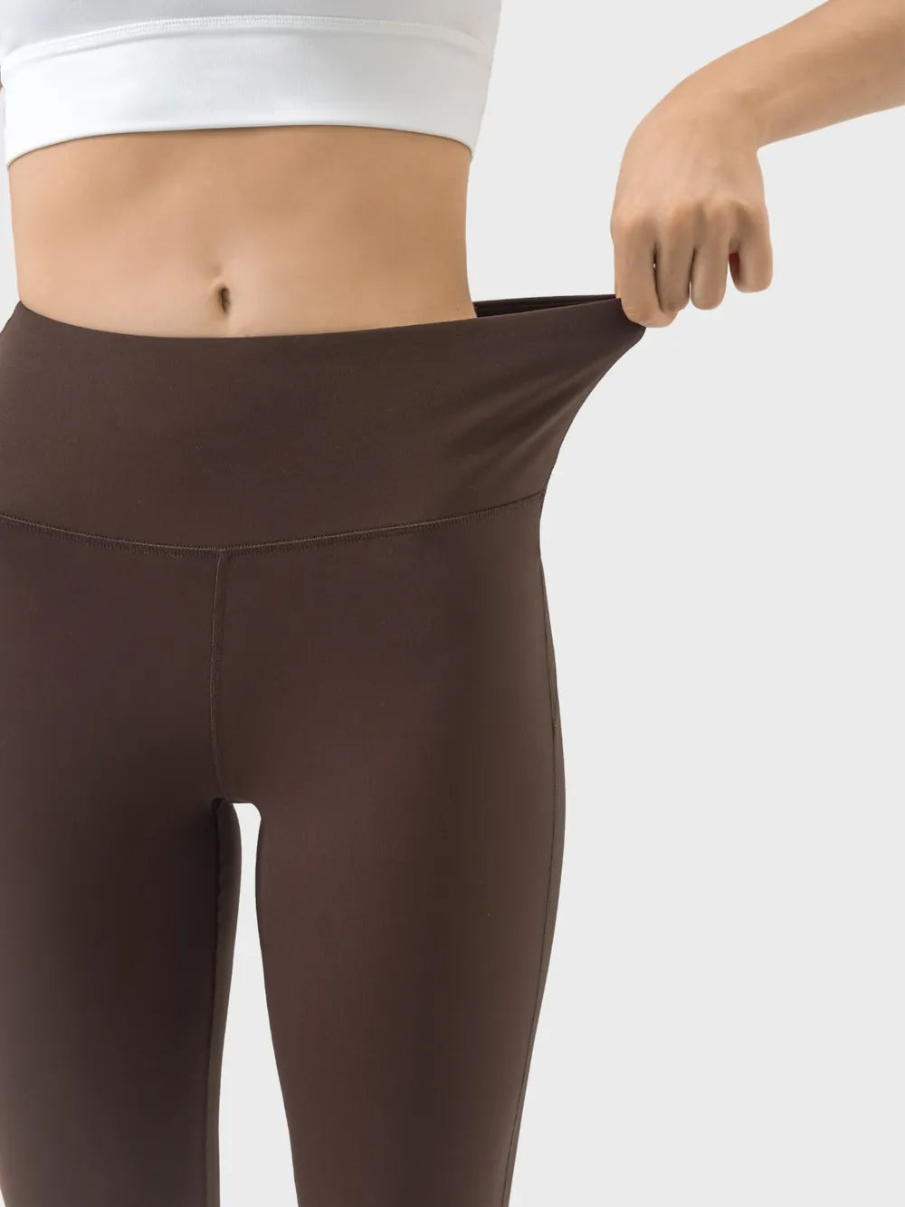 Brown leggings being stretched by a person on a white background