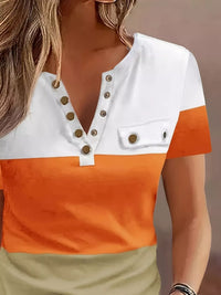 Color-blocked shirt with white, orange, and beige sections on a blurred background