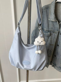 Light blue handbag with a cloud-shaped charm hanging on a hook, next to a denim jacket.