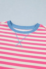 Close-up of a pink and white striped shirt with blue trim on a light blue background