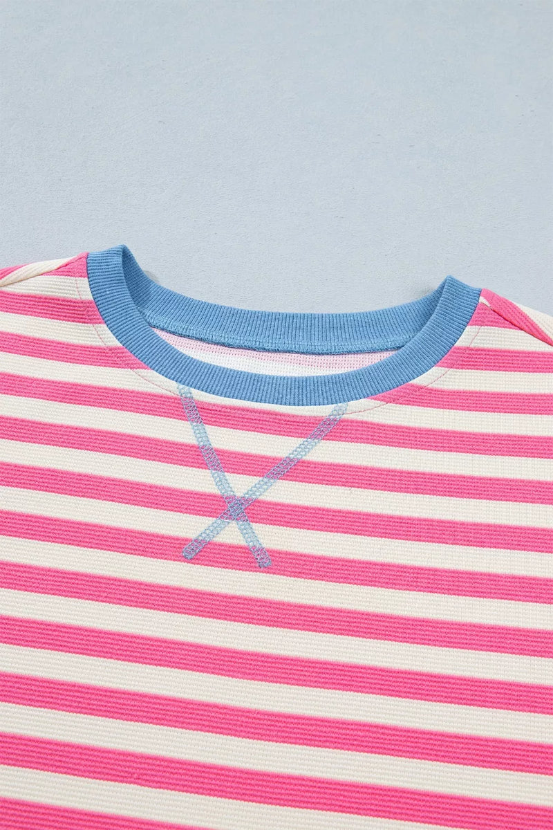 Close-up of a pink and white striped shirt with blue trim on a light blue background