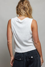 Person wearing a white sleeveless top and dark pants against a plain background