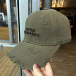 Distressed green cap with text held by a hand in an indoor setting