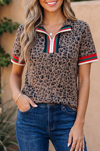 Woman wearing a leopard print top with red and green accents and blue jeans.