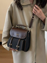 Person holding a two-toned leather bag with a beige coat