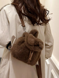 Person wearing a beige coat with a fluffy brown bag over their shoulder.