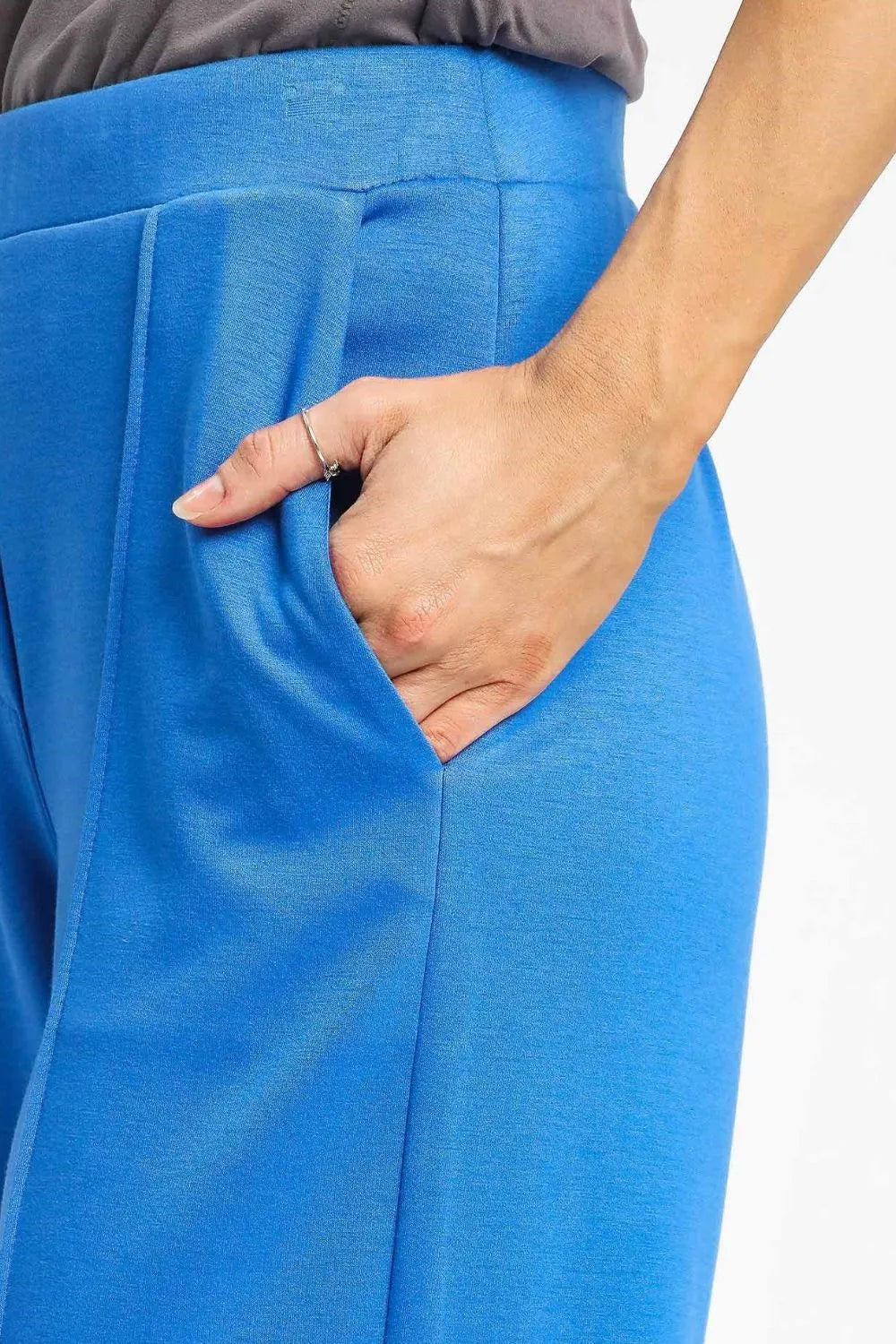 Close-up of blue pants with a hand in the pocket on a white background