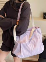 Person holding a light purple tote bag with a visible brand logo.