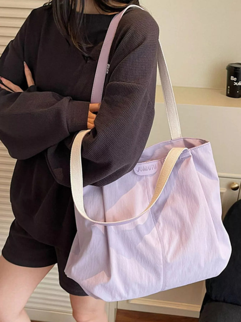 Person holding a light purple tote bag with a visible brand logo.