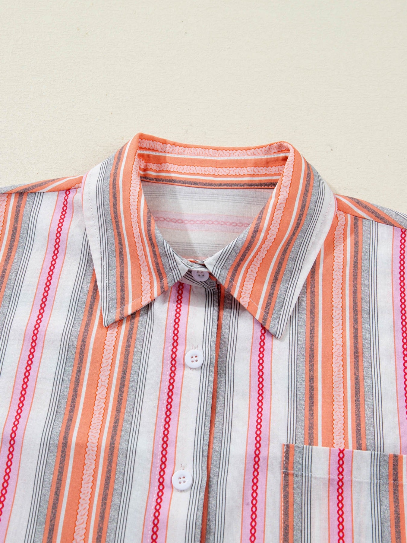 Striped shirt with orange, gray, and white pattern on a beige background