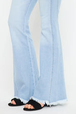 Light blue flared jeans worn with black sandals on a white background