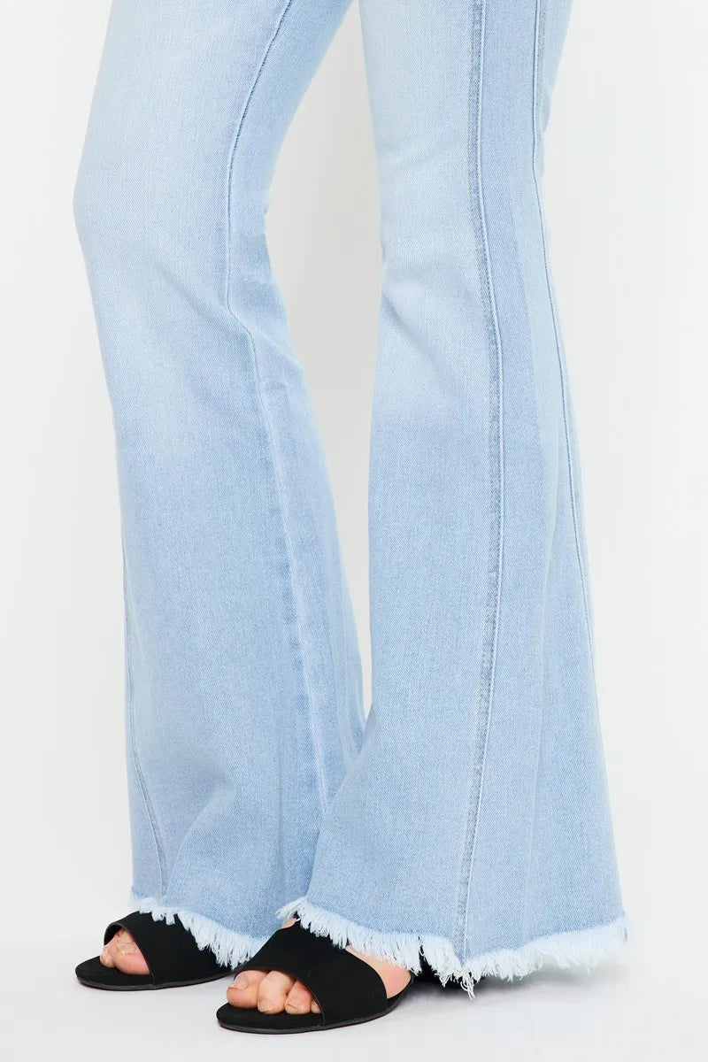 Light blue flared jeans worn with black sandals on a white background