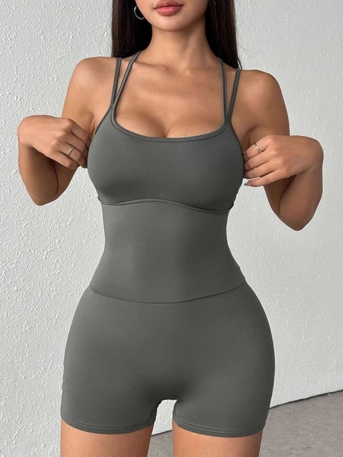 Woman wearing a gray athletic outfit against a white background