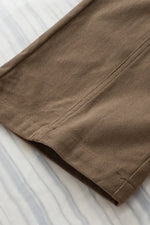 Brown pants on a white and gray striped fabric background