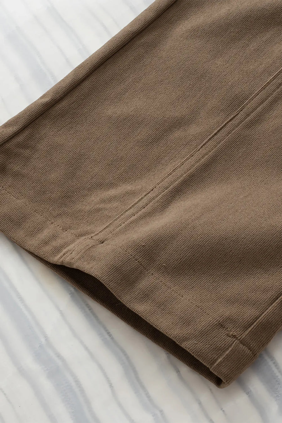 Brown pants on a white and gray striped fabric background