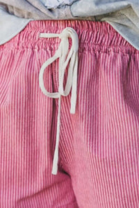 Close-up of pink striped pants with a white drawstring.