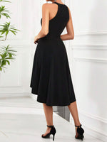 Woman wearing a black dress standing in a minimalistic room with white walls and a plant.
