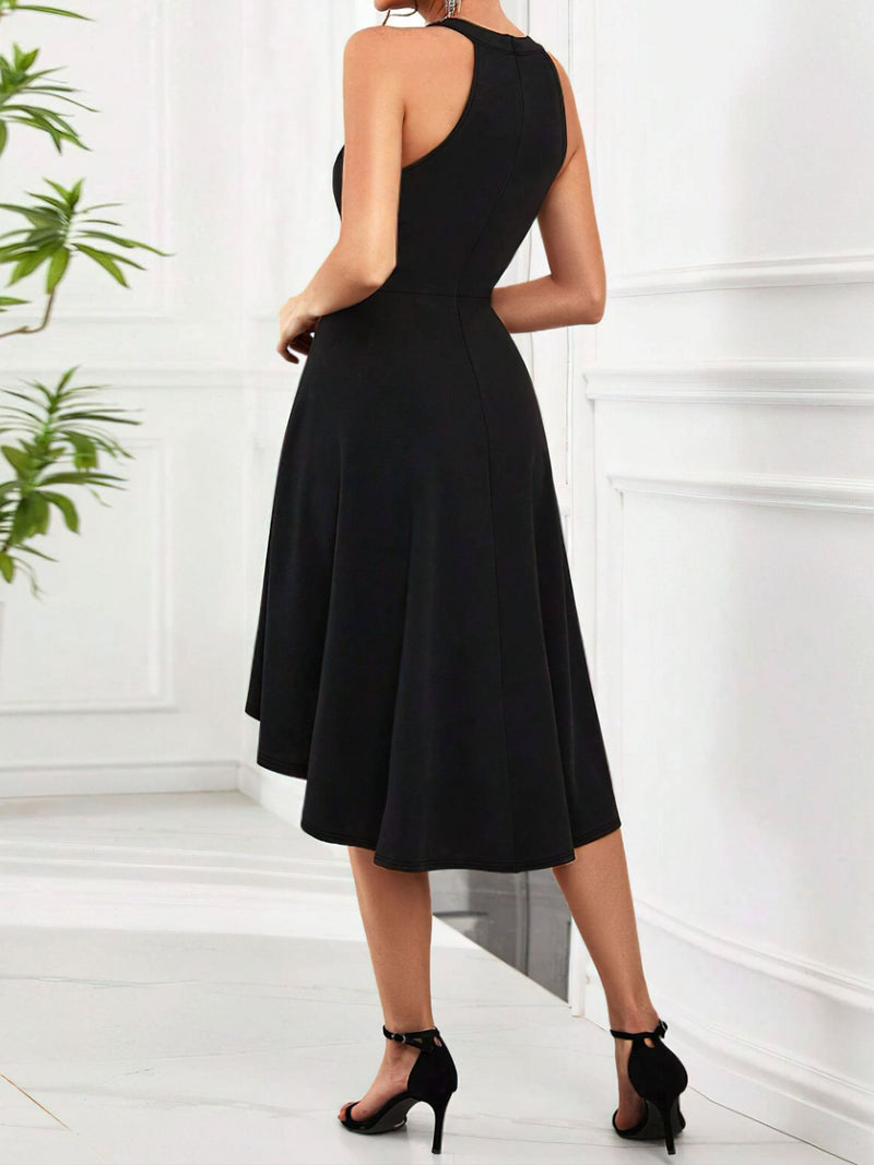 Woman wearing a black dress standing in a minimalistic room with white walls and a plant.