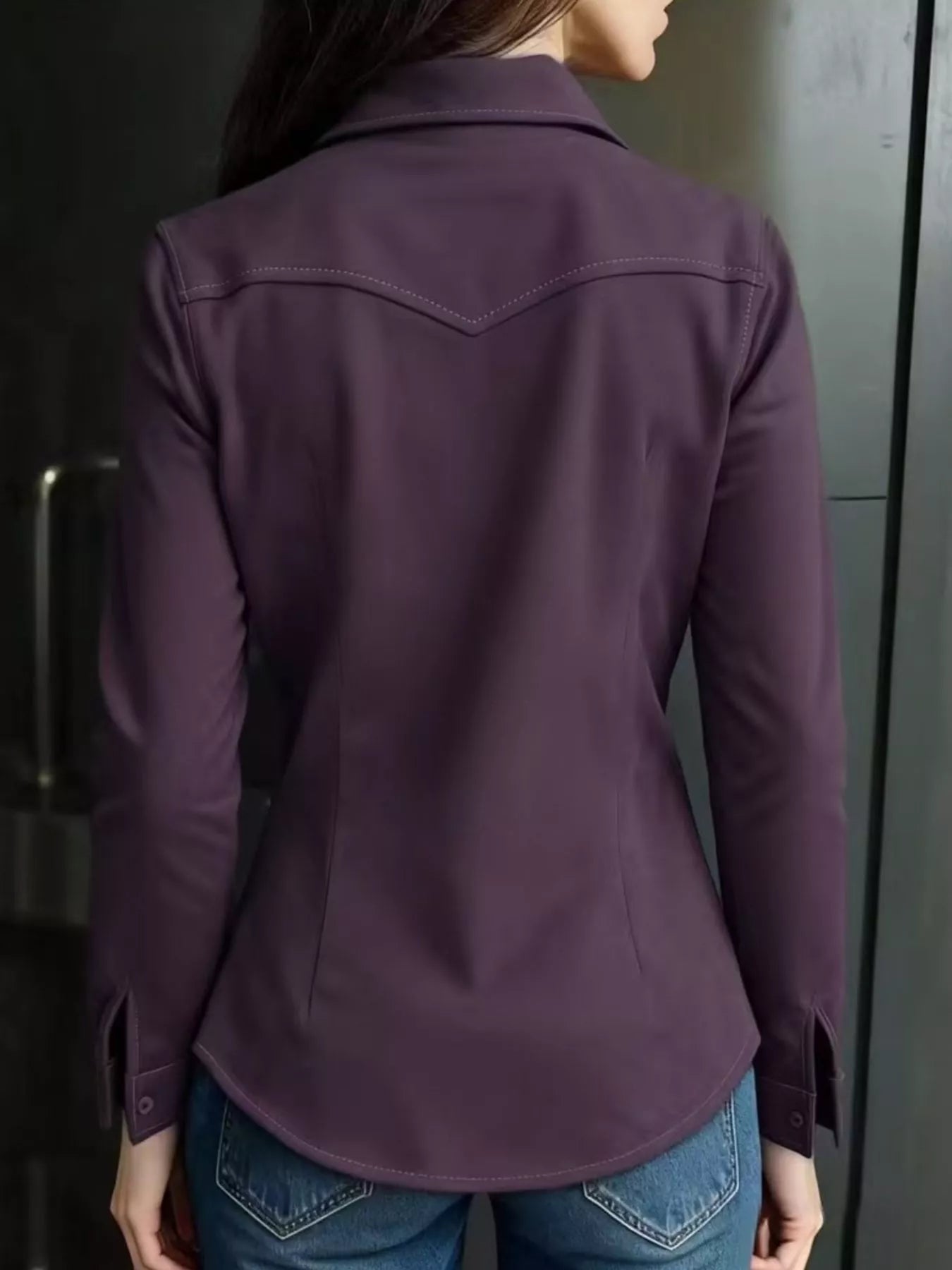 Person wearing a purple jacket and blue jeans against a neutral background