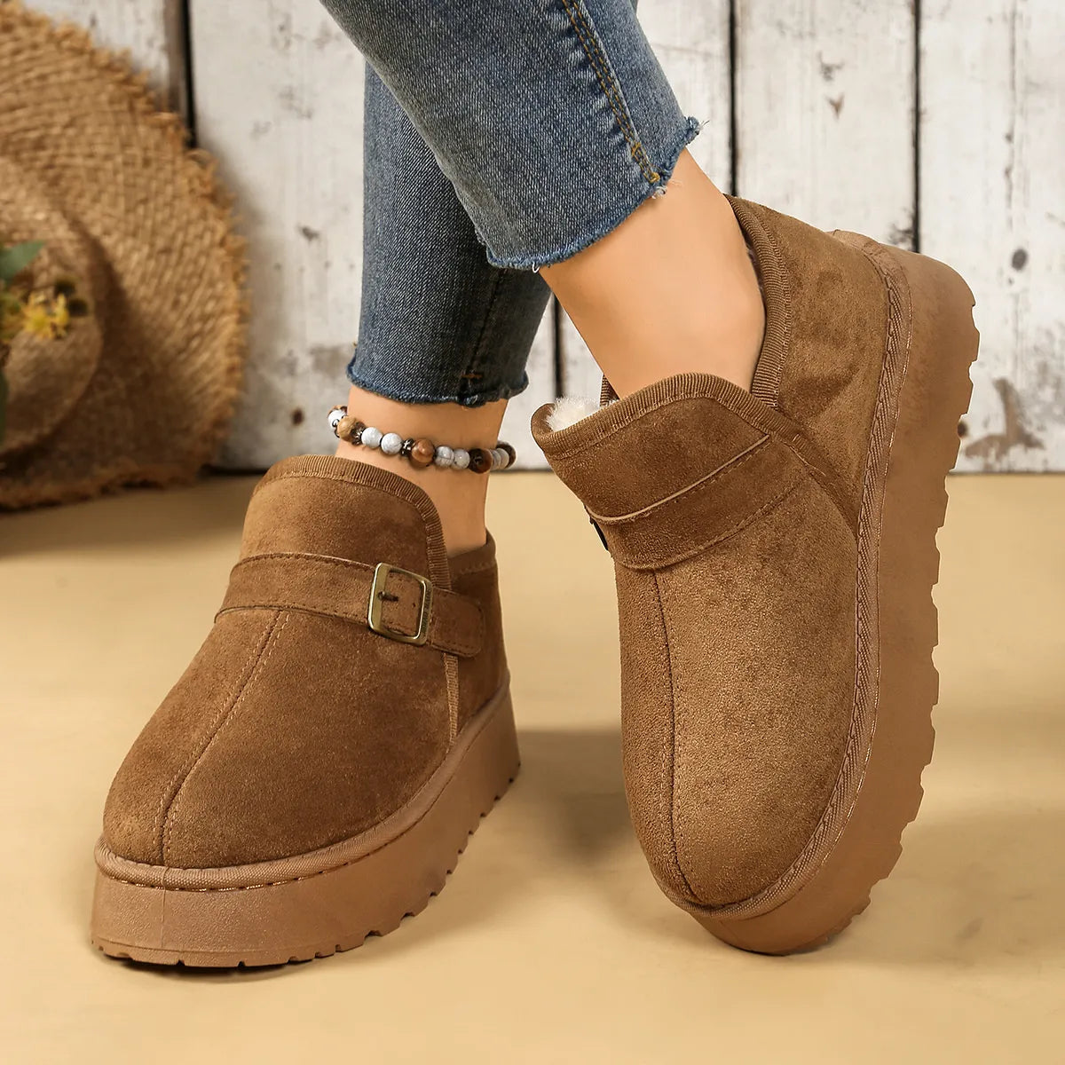 Brown suede shoes worn with blue jeans on a neutral background