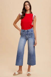 Woman wearing a red top and blue jeans on a beige background