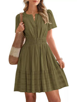 Woman wearing a green dress holding a striped bag on a white background