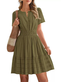 Woman wearing a green dress holding a striped bag on a white background