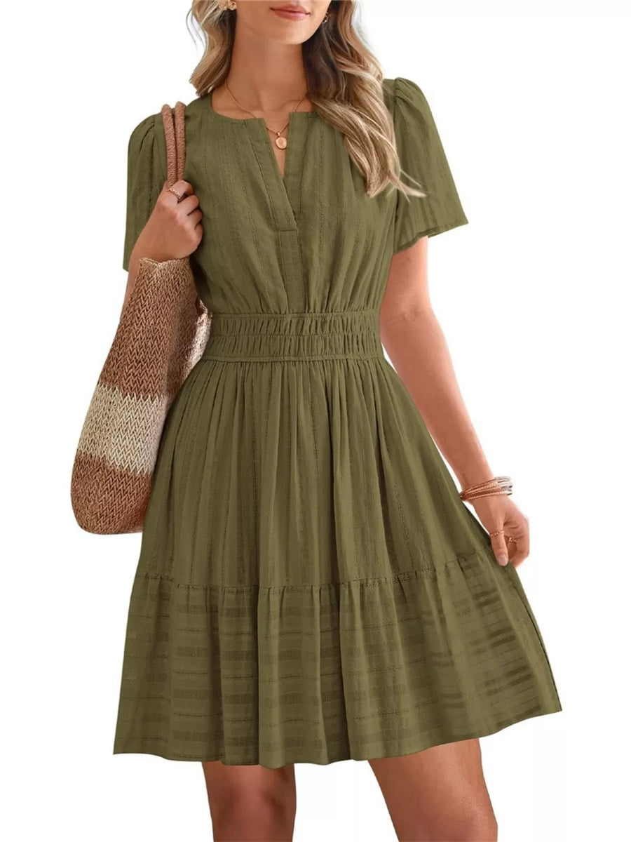 Woman wearing a green dress holding a striped bag on a white background