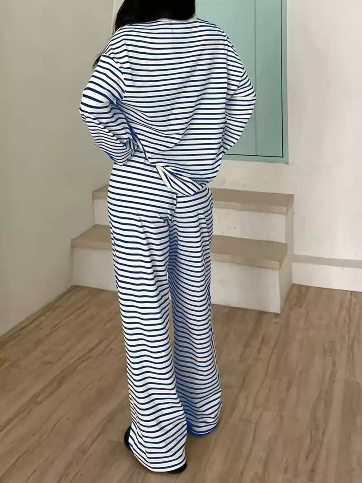 Person wearing a blue and white striped outfit standing on a wooden floor.