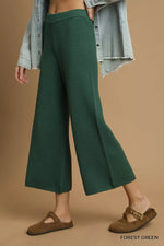 Person wearing forest green pants with a beige background