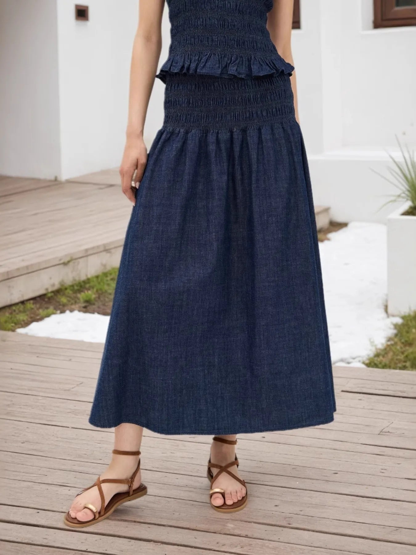 Woman wearing a navy blue dress standing on a wooden deck.