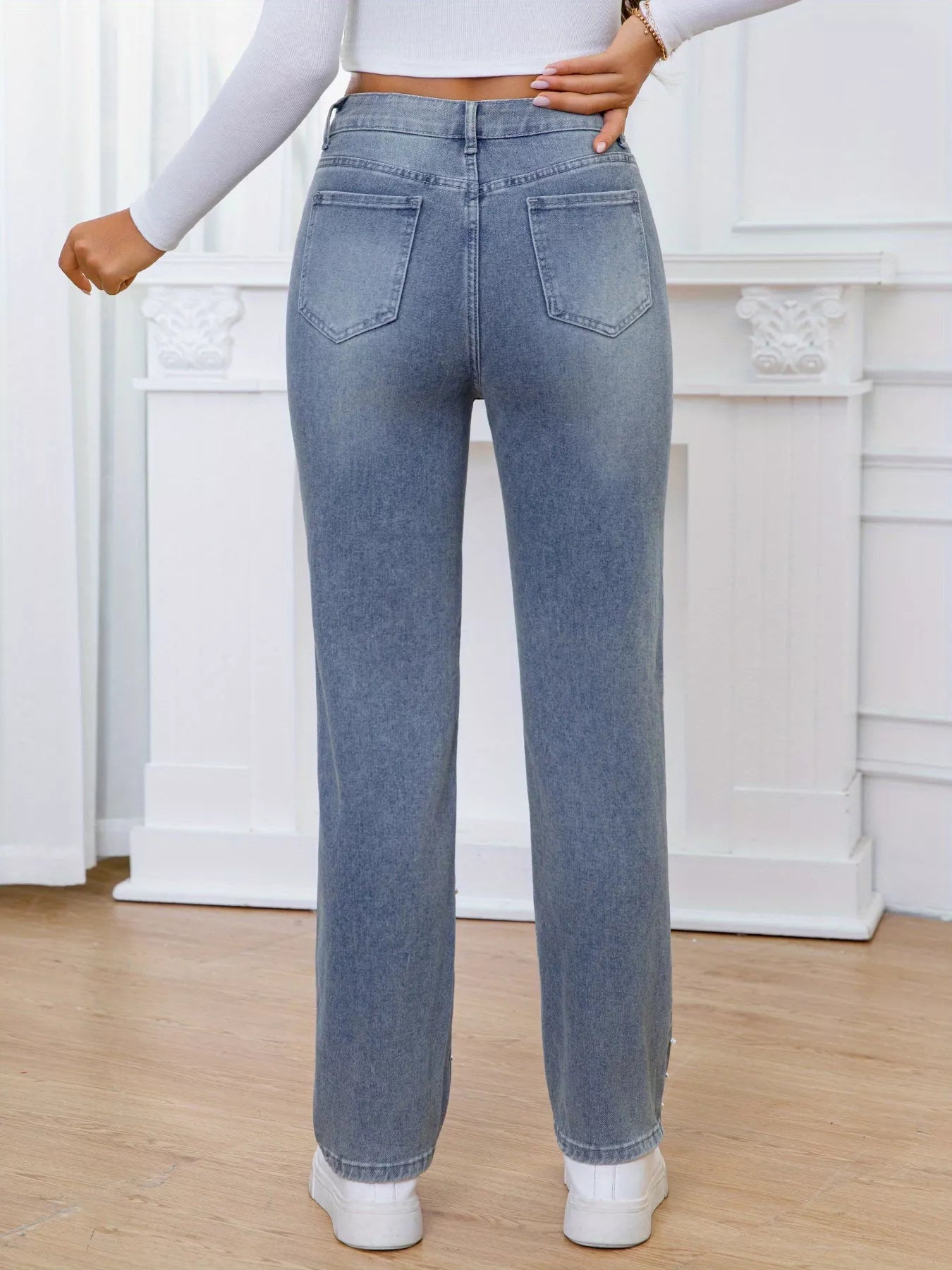 Person wearing light blue jeans in a minimalistic room.