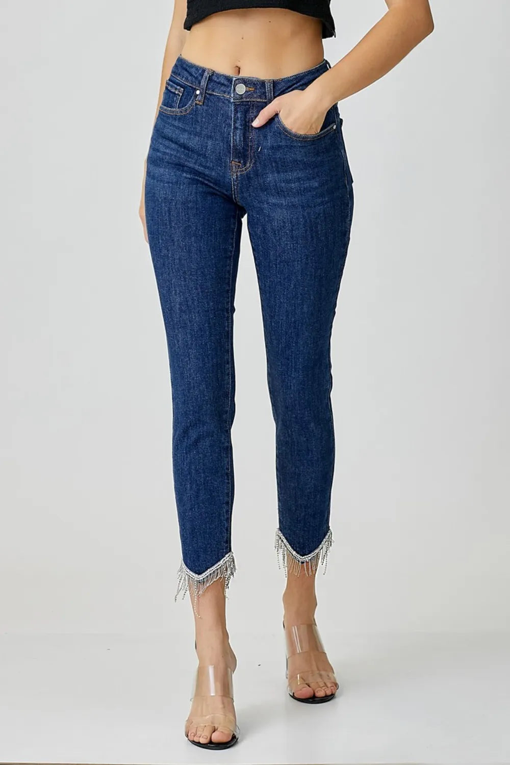 Blue jeans with frayed hem worn by a person on a white background